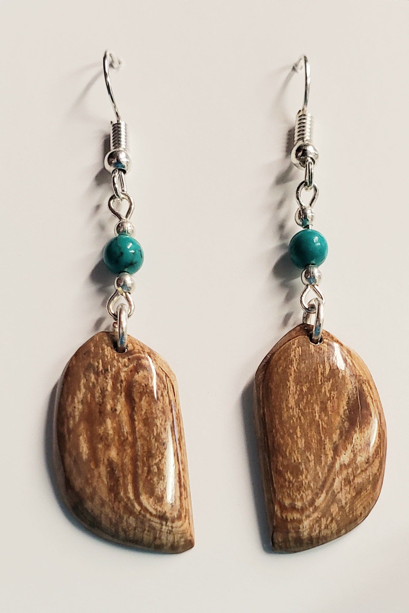 These long Feather shaped earrings are hand crafted from Fossil Mammoth Ivory found in Canada. The Ivory is about 35,000 years old and is all naturally colored just the way it came out of the ground. This highlighted with Howlite Turquoise beads.

Hung on Stainless steel earrings.